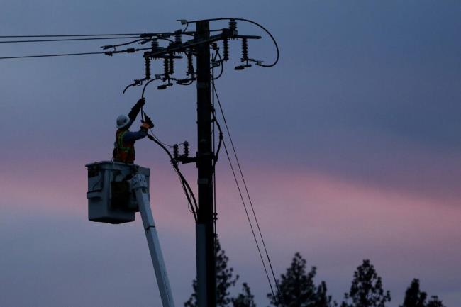 FILE - In this Nov. 26, 2018, file photo, a Pacific Gas & Electric lineman works to repair a power line in fire-ravaged Paradise, Calif.  (AP Photo/Rich Pedroncelli, File)