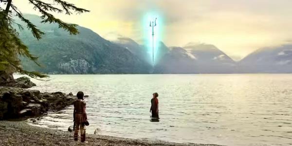 Percy Jackson is standing in the water looking up with Poseidon's trident above him. Annabeth watches from the shoreline in Percy Jackson and the Olympians.