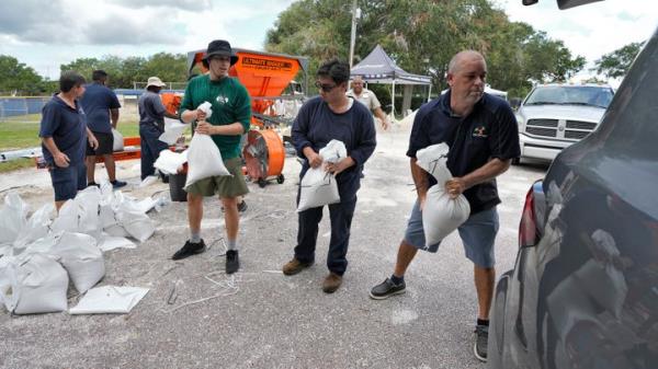 Members of the Tampa, Fla., Parks and Recreation Dept., help residents load sandbags on Aug. 28, 2023, in Tampa, Fla. 